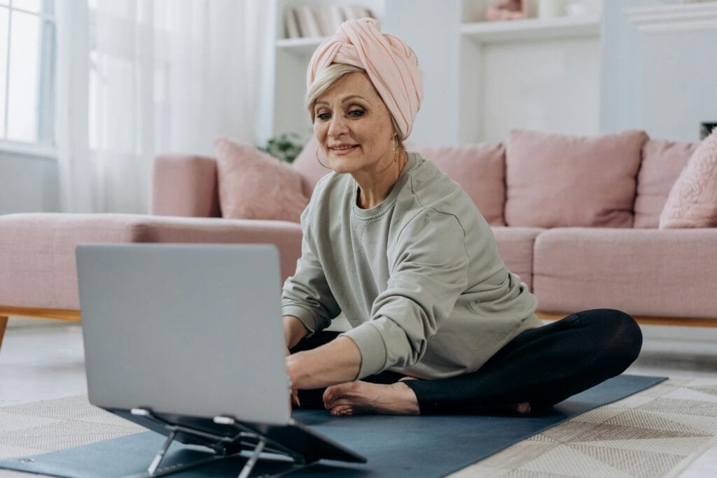 pexels-photo-7530014-7530014 Elderly Woman Sitting on Yoga Mat While Using a Laptop